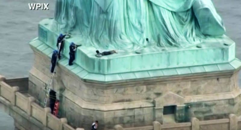 Mujer escala la Estatua de la Libertad