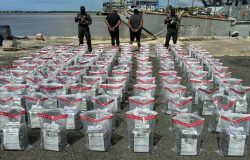 Un grupo de hombres parados junto a bolsas de plástico. 675 paquetes de cocaina