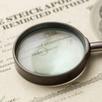 Certificado de acciones antiguo con lupa enfocando detalles.